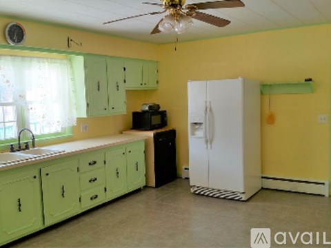 A kitchen with green cabinets and a white refrigerator.