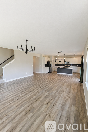 A spacious living room with wooden flooring and a chandelier.