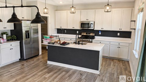 A kitchen with white cabinets and a black island.