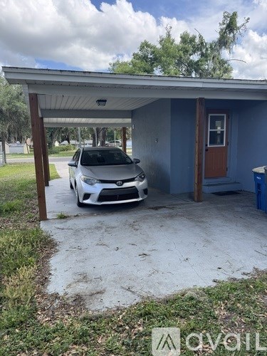 A white car is parked in front of a blue house.