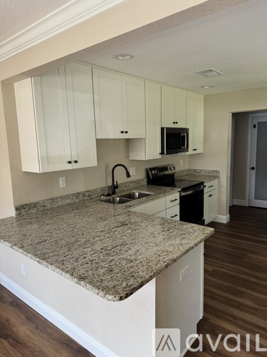 A kitchen with granite countertops and white cabinets.