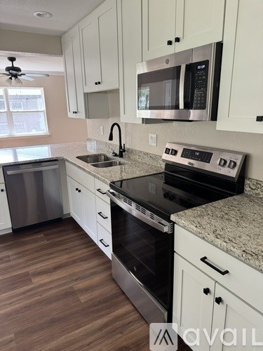 A kitchen with white cabinets and a black stove top oven.