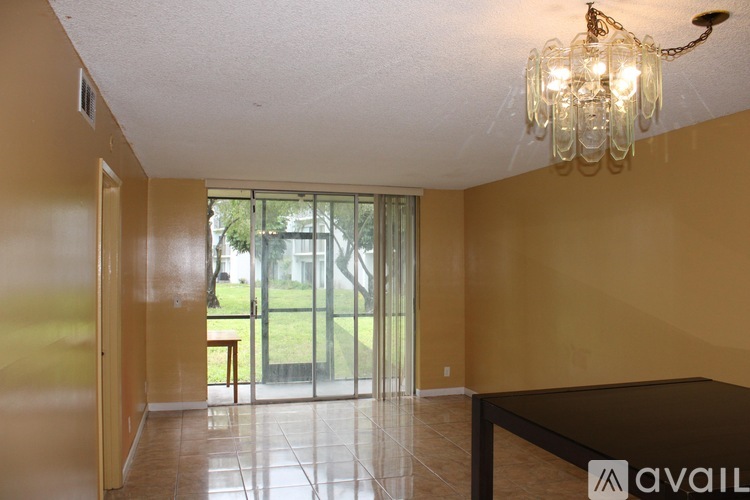 A room with a chandelier and a sliding glass door leading to a patio.