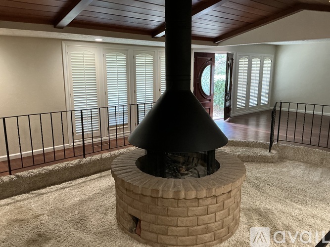 A black chimney in a room with a brick base.