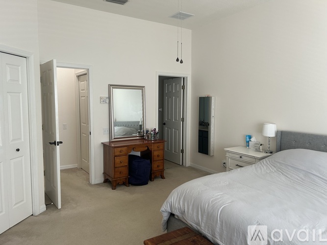 A bedroom with a large bed, a dresser with a mirror, and a nightstand with a lamp.