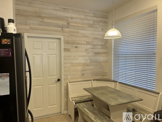 A kitchen with a black fridge, a wooden table and chairs, and a white door.