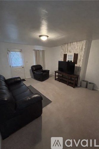 A living room with a black leather couch and a television.