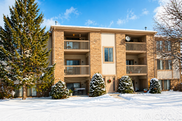 Apartment building with snow on the ground and trees.