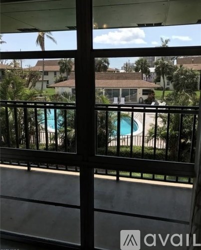 A view from a balcony looking out at a pool and houses.