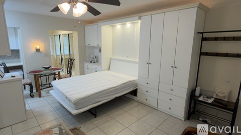 A bedroom with a bed, a chair, a table, and a cabinet.