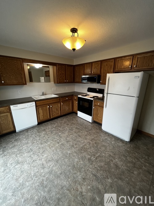 A kitchen with white appliances and wooden cabinets.
