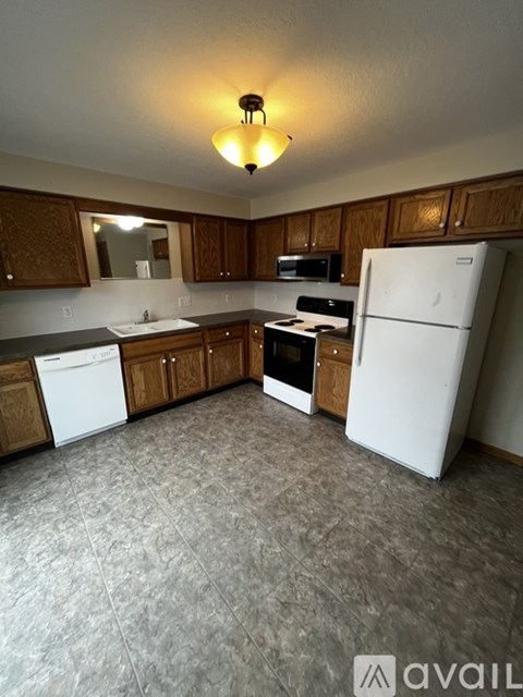 A kitchen with white appliances and wooden cabinets.