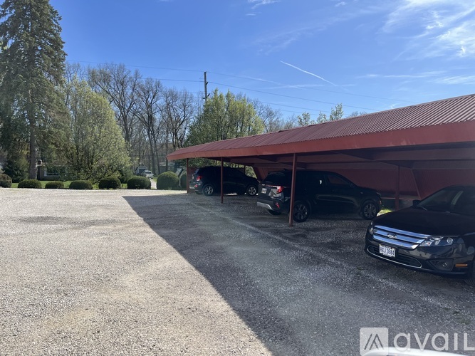 A parking lot with a red roofed building and cars parked in front.