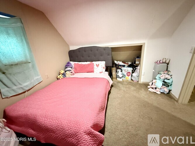 A bedroom with a pink bedspread and a bed with a black headboard.