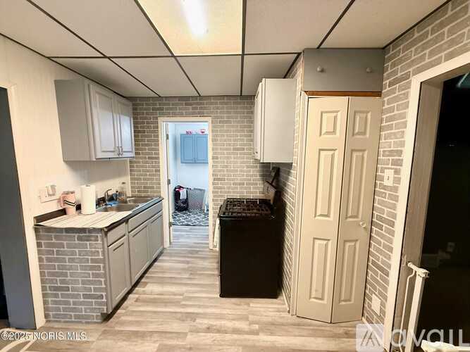 A kitchen with a brick wall and a white door.