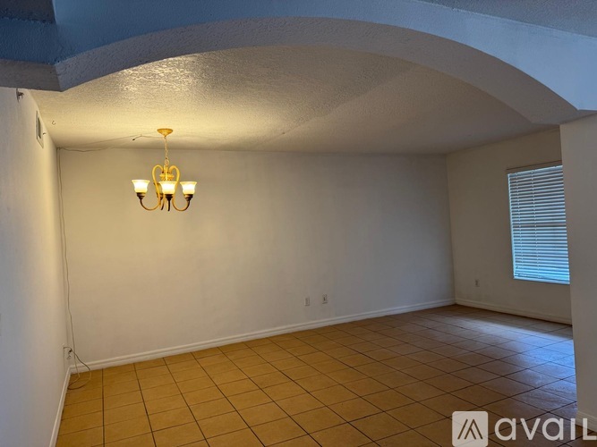 A room with a chandelier and tiled floor.