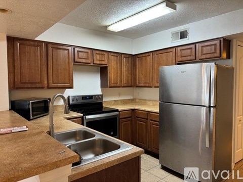 A kitchen with wooden cabinets and a stainless steel refrigerator.