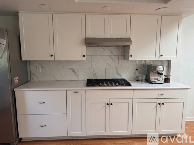 A kitchen with white cabinets and a marble backsplash.