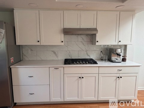 A kitchen with white cabinets and a marble backsplash.