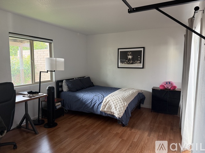 A bedroom with a bed, desk, chair, and a window.