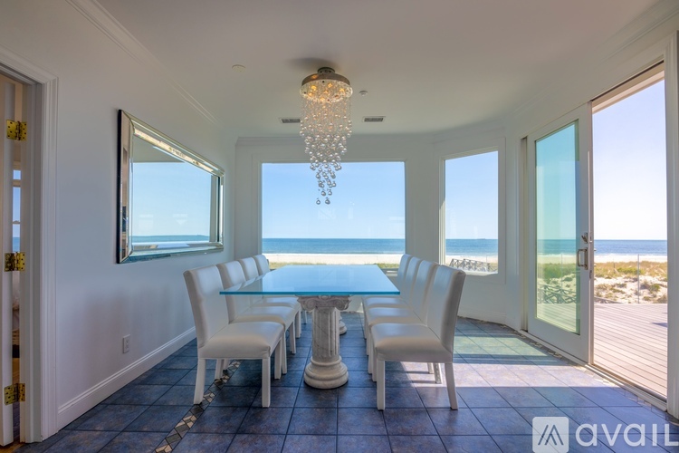 A dining room with a table and chairs overlooking the beach.