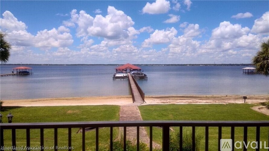 A view of a lake with a pier and a house with a red roof.