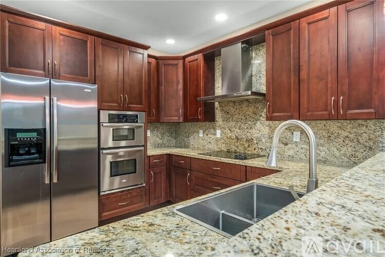 A kitchen with brown cabinets and granite countertops.