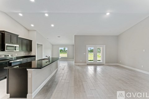 A spacious kitchen with black appliances and a black countertop.
