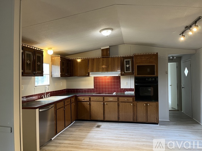 A kitchen with wooden cabinets and a red tile backsplash.