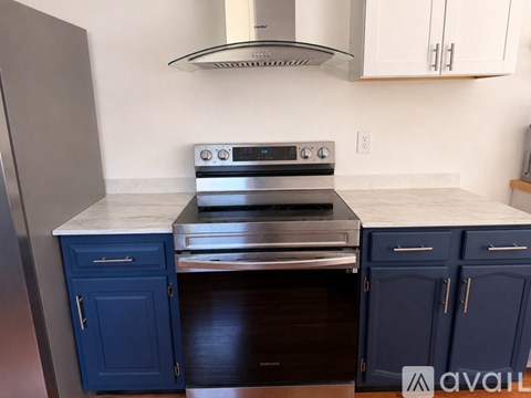 A kitchen with a stove top oven and blue cabinets.