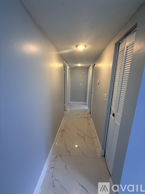 A long hallway with marble floors and white walls.