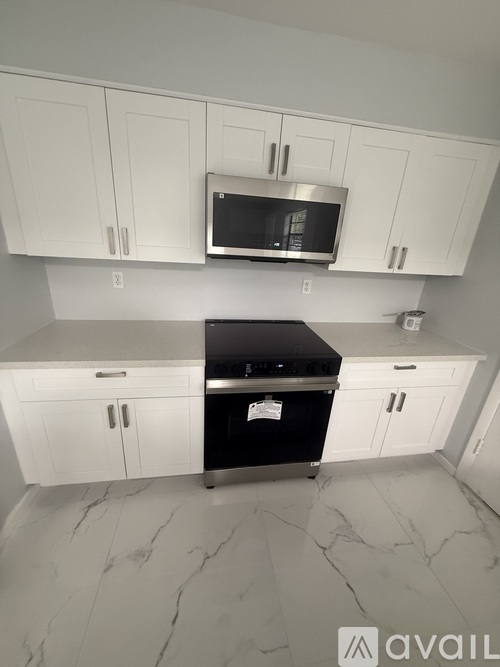 A kitchen with white cabinets and a black countertop.