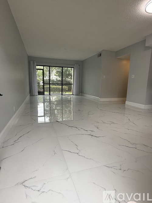 A spacious room with marble flooring and a view of the outdoors through the glass doors.