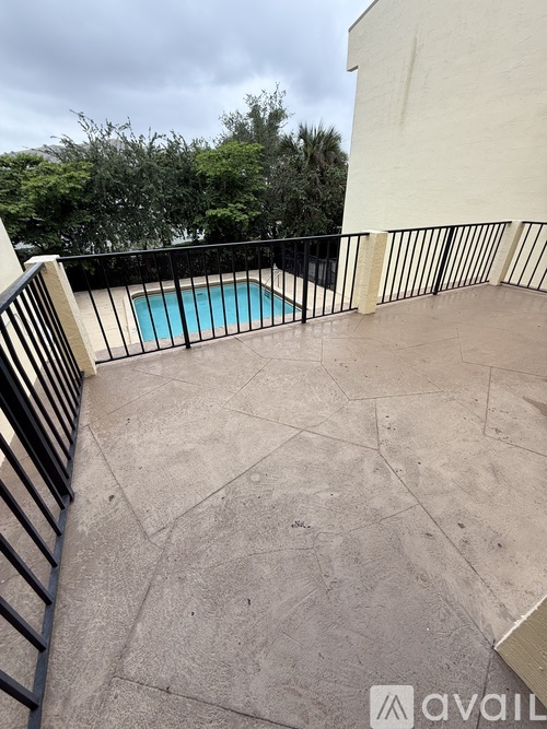 A patio with a pool and a black railing.