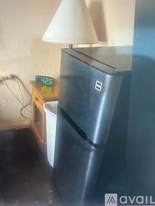 A black refrigerator with a digital clock showing 4:25 on a wooden table.