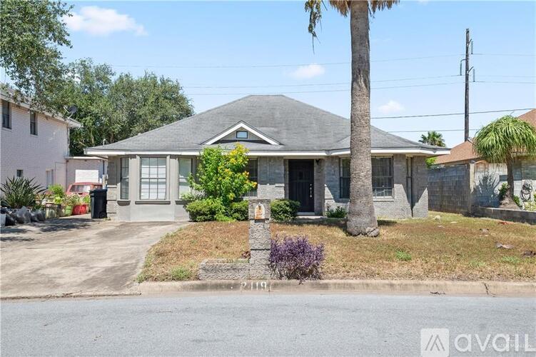 A house with a grey roof and a palm tree in front.