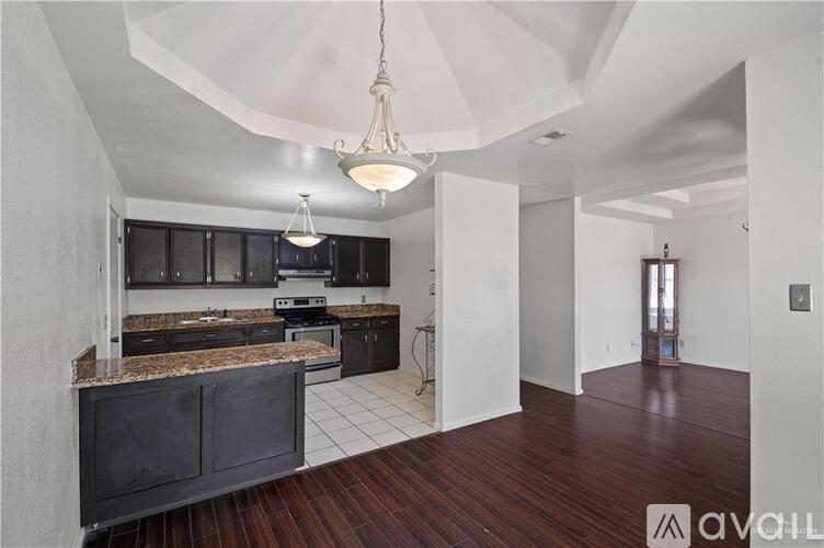 A modern kitchen with dark wood floors and white walls.