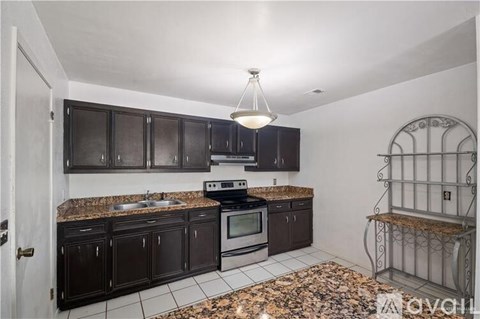A kitchen with black cabinets and a granite countertop.