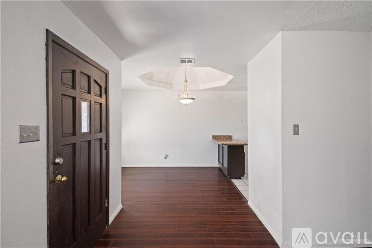 A hallway with a wooden floor and a brown door.