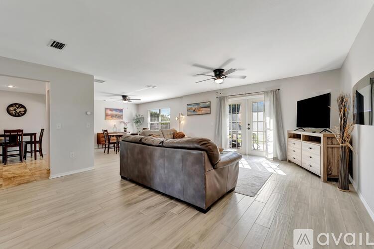 A spacious living room with a grey sofa and a wooden floor.