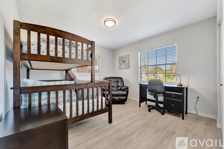 A bedroom with a bunk bed and a desk with a chair.