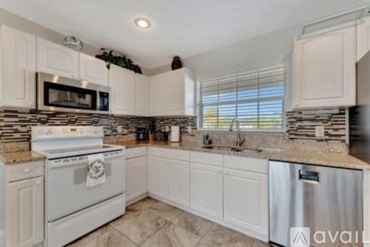 A kitchen with white cabinets and a stone countertop.