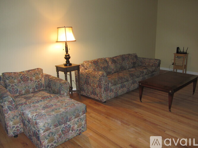 A lamp on a table in a room with a couch and ottoman.