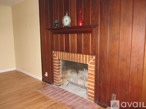 A fireplace with a clock and a bottle on top of it.