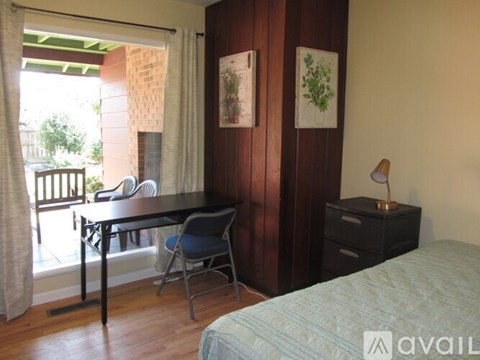 A bedroom with a bed, desk, and chair.
