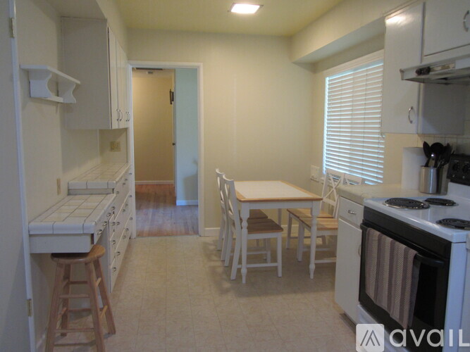A kitchen with white appliances and a table with chairs.