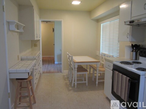 A kitchen with white appliances and a table with chairs.