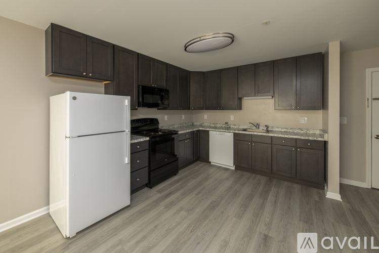 A kitchen with a white refrigerator and dark brown cabinets.