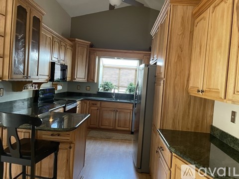 A kitchen with wooden cabinets and a black countertop.