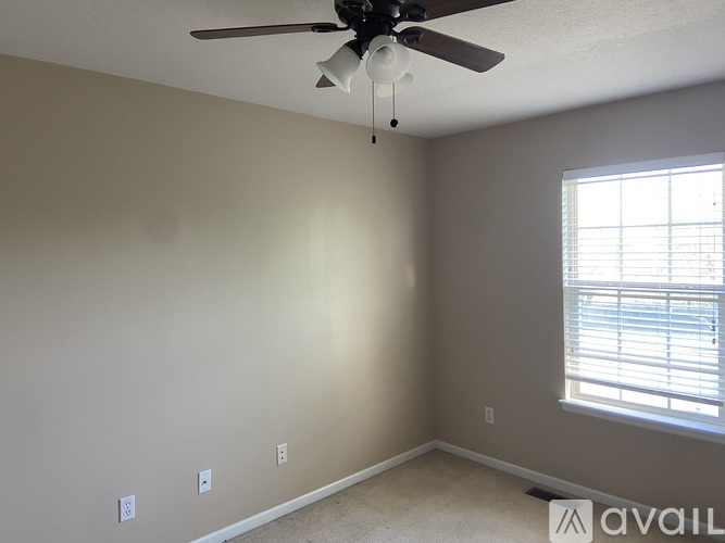 A room with a ceiling fan and a window with blinds.